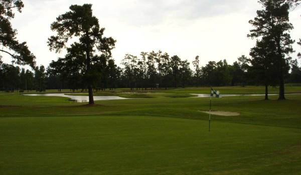 view of golf course green with sand trapview of golf course at sunset with sand traps